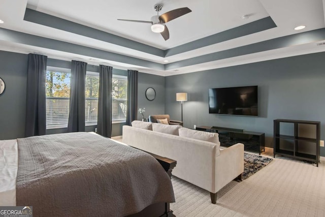 carpeted bedroom with ceiling fan and a tray ceiling