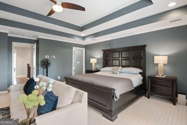 bedroom featuring ceiling fan, light colored carpet, ornamental molding, and a tray ceiling