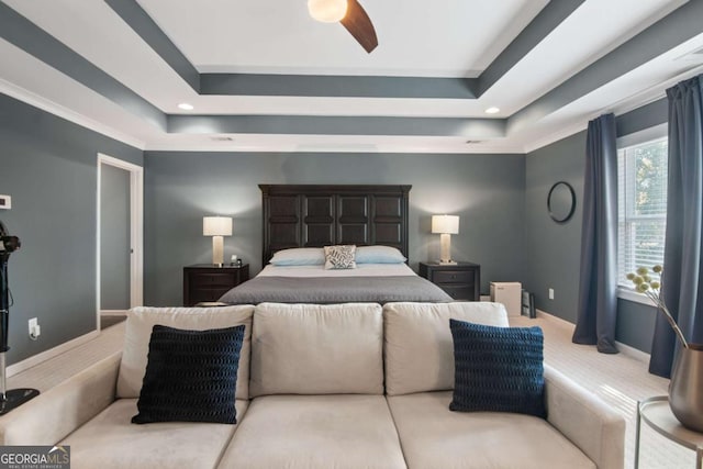 carpeted bedroom featuring a raised ceiling and ceiling fan