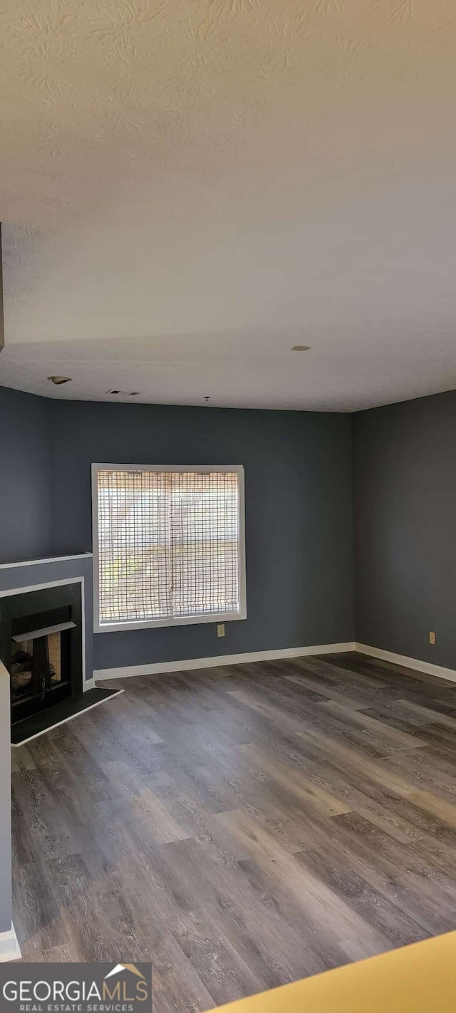 unfurnished living room with hardwood / wood-style floors and a textured ceiling