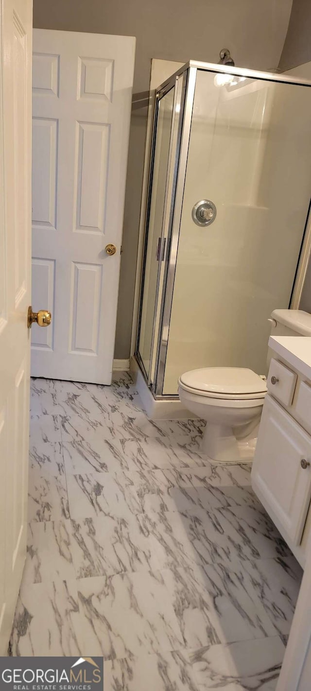 bathroom featuring vanity, a shower with shower door, and toilet