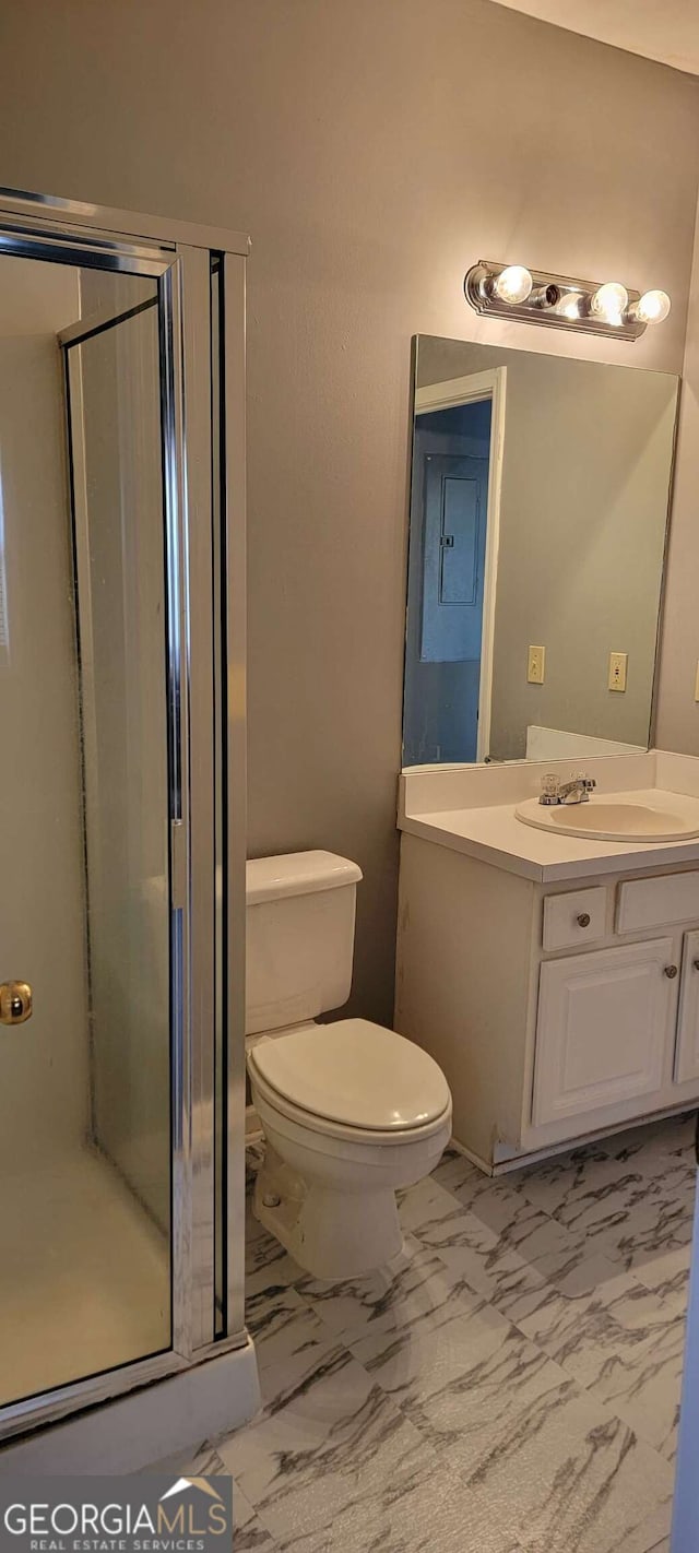 bathroom featuring vanity, an enclosed shower, and toilet