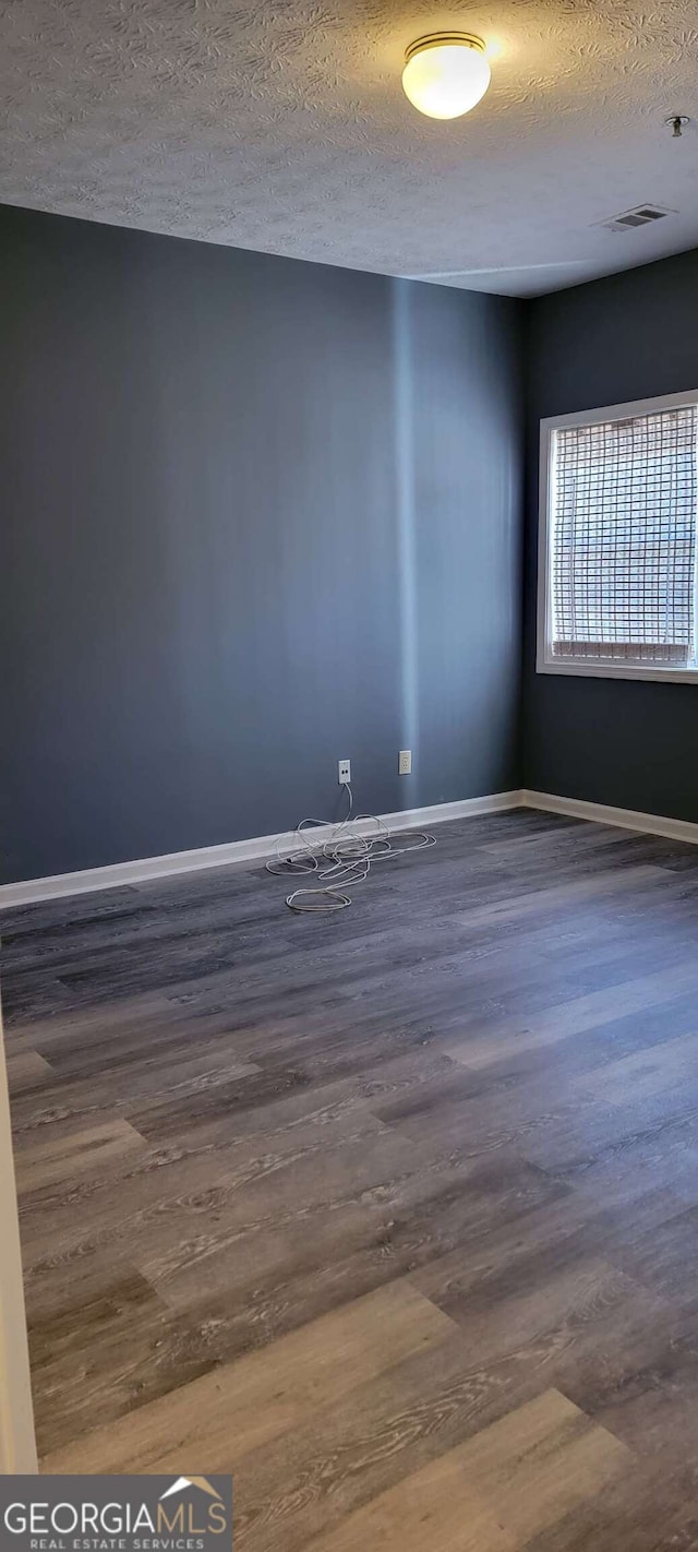 unfurnished room with a textured ceiling and dark hardwood / wood-style flooring