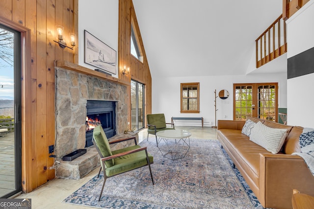 living room featuring a stone fireplace, wooden walls, high vaulted ceiling, and french doors