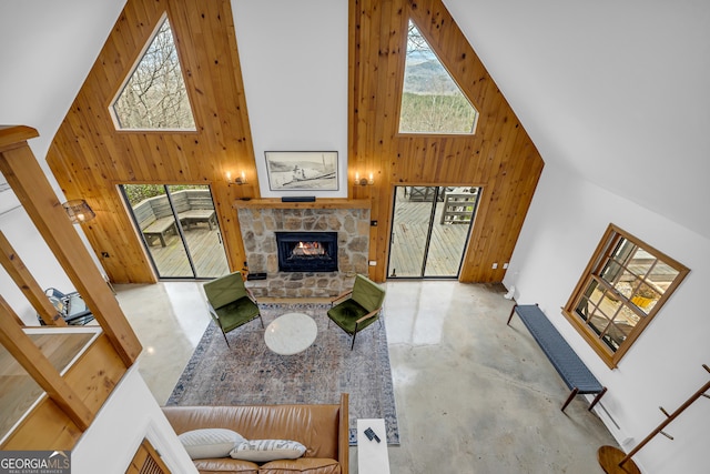 living room with a towering ceiling, a fireplace, and wood walls