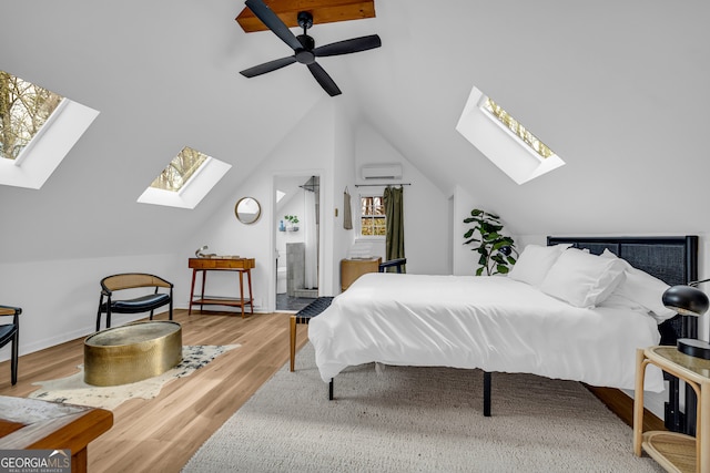 bedroom featuring vaulted ceiling, connected bathroom, a wall mounted AC, and light wood-type flooring