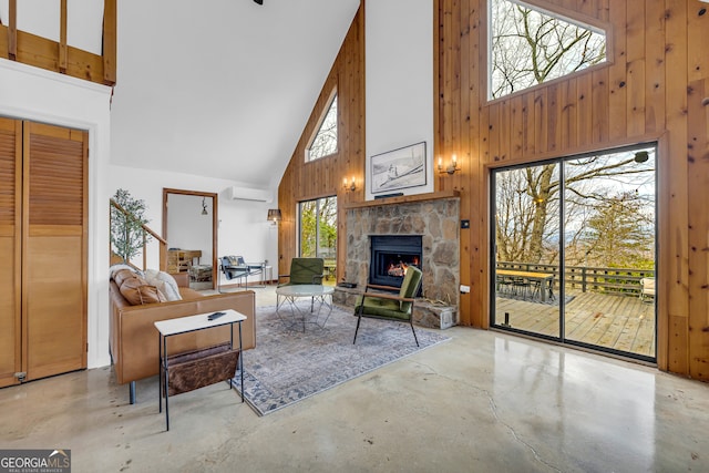 living room featuring a fireplace, high vaulted ceiling, a wall mounted AC, and wood walls