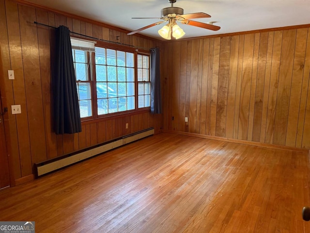 empty room featuring a baseboard heating unit, light hardwood / wood-style flooring, ceiling fan, and wood walls