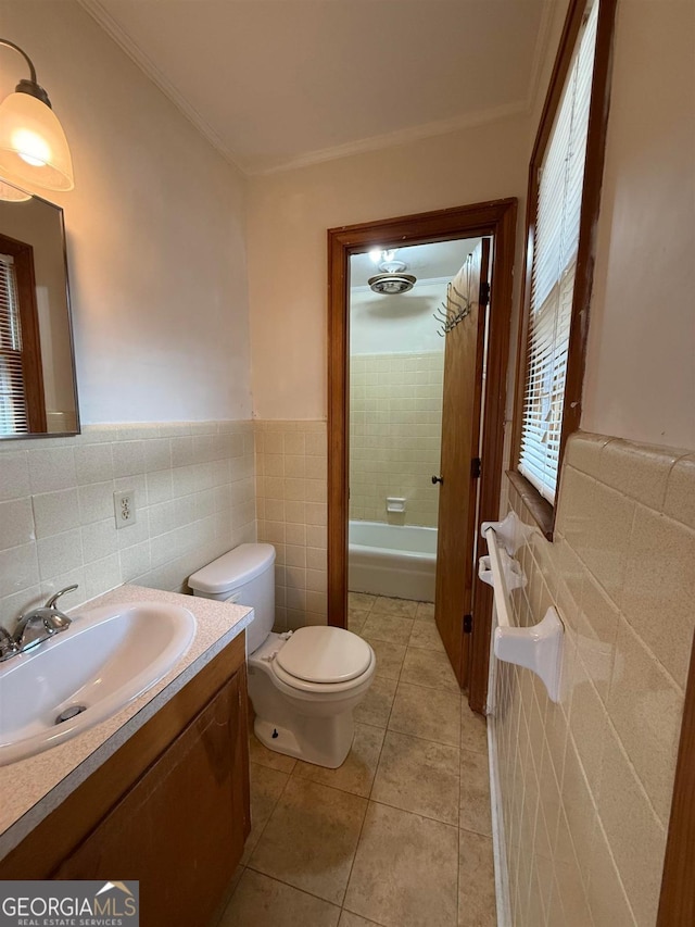 bathroom with crown molding, tile patterned flooring, tile walls, vanity, and toilet