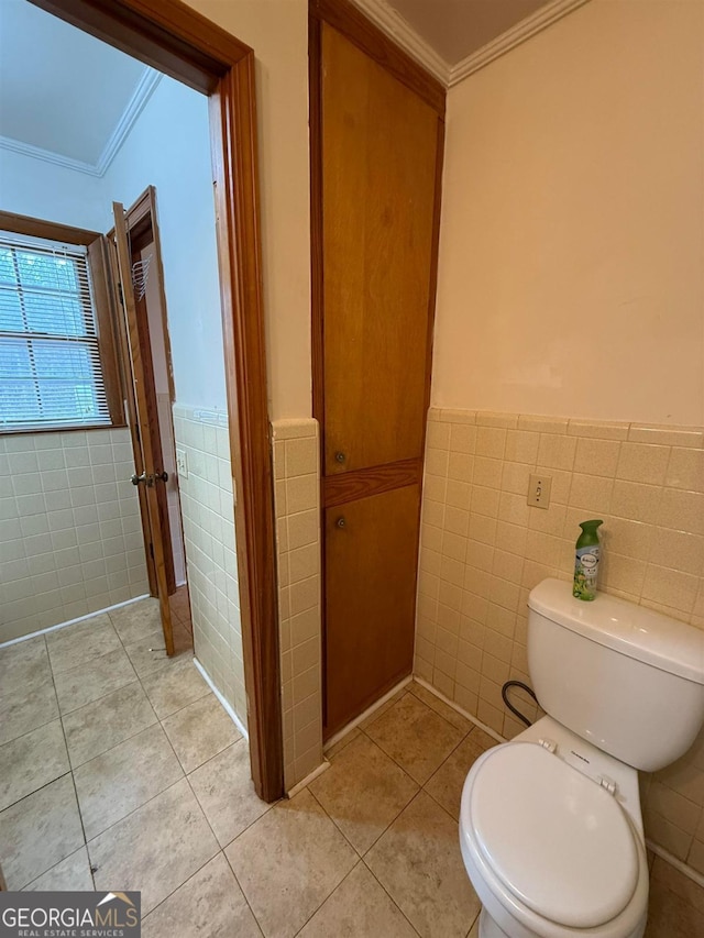 bathroom with tile patterned flooring, crown molding, and tile walls