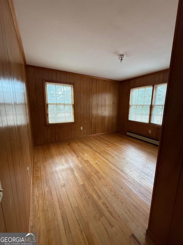 empty room with a baseboard radiator and light hardwood / wood-style floors