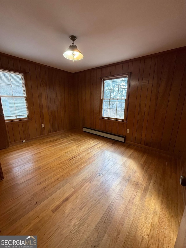 unfurnished room with baseboard heating and light hardwood / wood-style floors