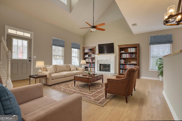 living room with a healthy amount of sunlight, a fireplace, light hardwood / wood-style floors, and high vaulted ceiling