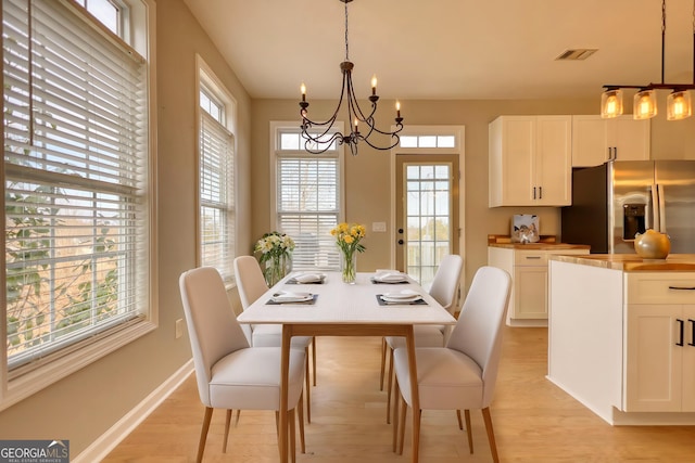 dining space with a notable chandelier and light hardwood / wood-style flooring