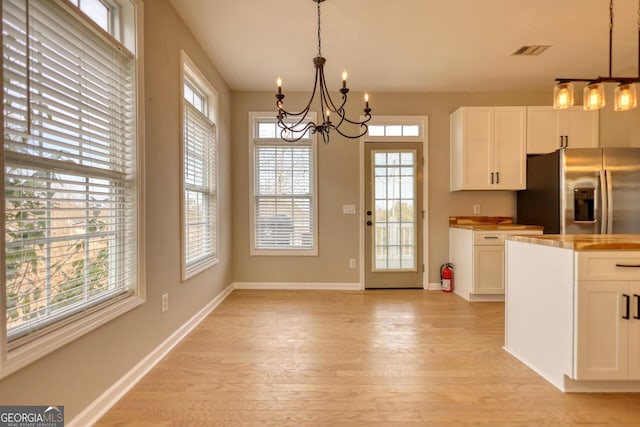 kitchen featuring pendant lighting, white cabinetry, stainless steel fridge with ice dispenser, a chandelier, and light wood-type flooring