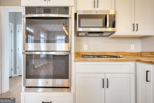 kitchen featuring wood counters, appliances with stainless steel finishes, light wood-type flooring, and white cabinets