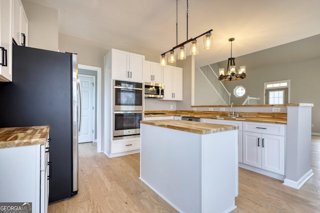 kitchen with wood counters, appliances with stainless steel finishes, sink, and white cabinets