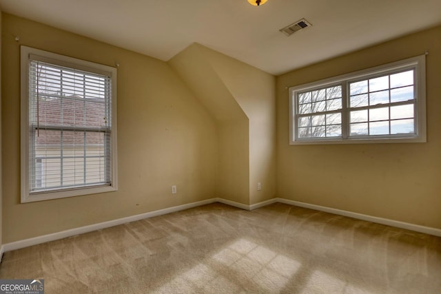 bonus room with vaulted ceiling, a healthy amount of sunlight, and light colored carpet