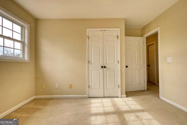 unfurnished bedroom featuring light carpet and a closet