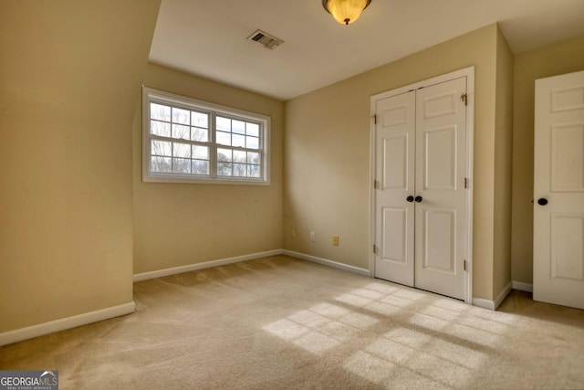 unfurnished bedroom with light carpet and a closet