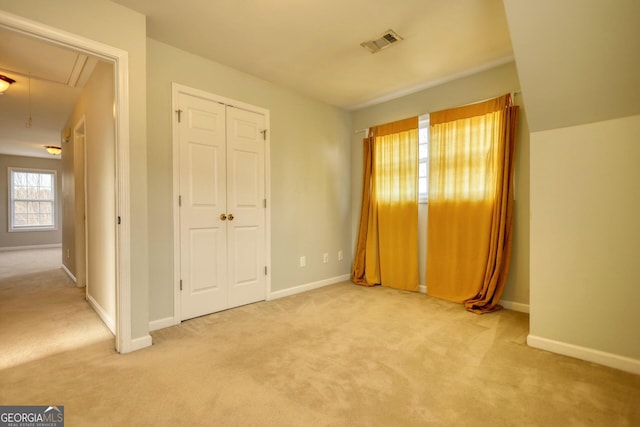 unfurnished bedroom with light colored carpet and a closet