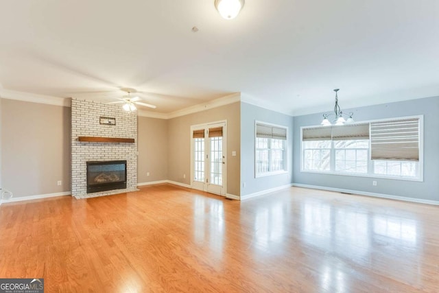 unfurnished living room featuring ornamental molding, a fireplace, light wood-type flooring, and french doors