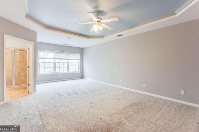 carpeted spare room with a tray ceiling, ornamental molding, and ceiling fan