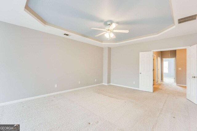 carpeted spare room featuring a raised ceiling and ceiling fan