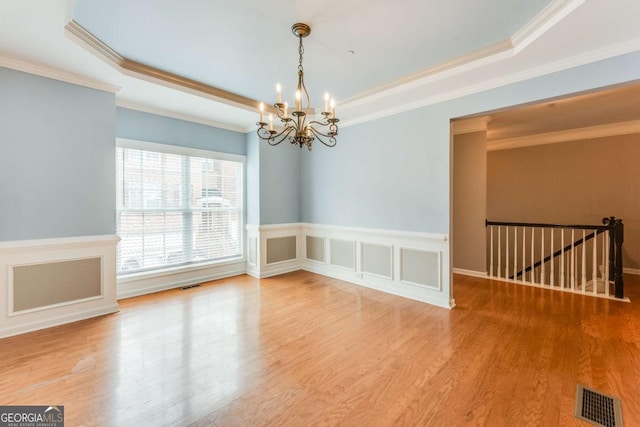 unfurnished room with crown molding, hardwood / wood-style floors, a tray ceiling, and a chandelier