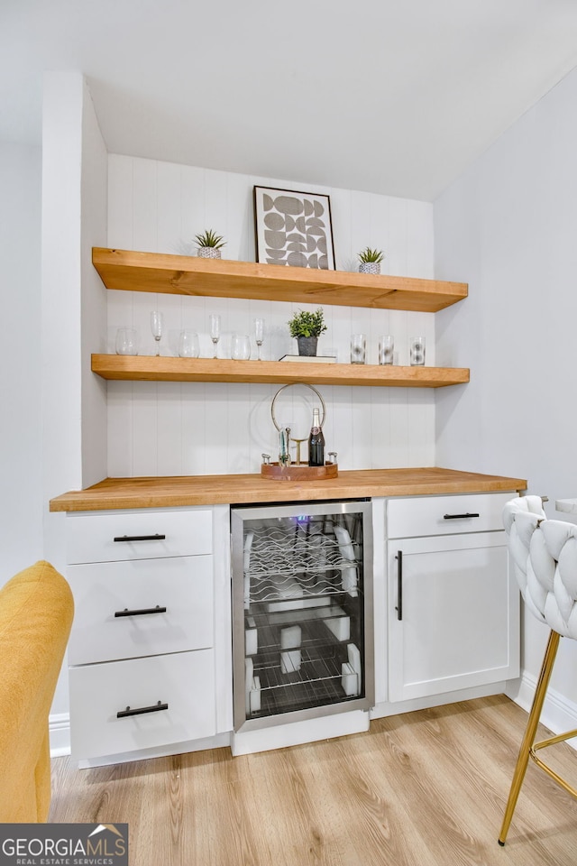 bar featuring wine cooler, white cabinetry, butcher block counters, and light hardwood / wood-style flooring