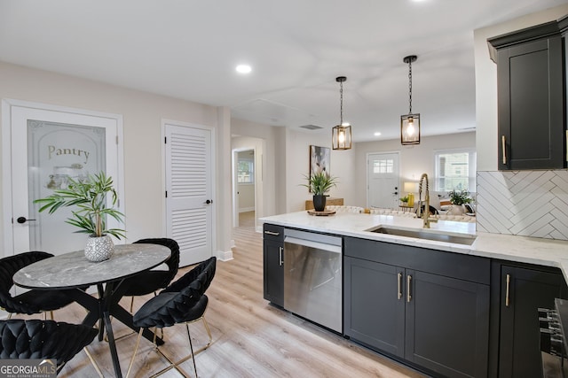 kitchen featuring decorative light fixtures, dishwasher, sink, light stone counters, and light wood-type flooring