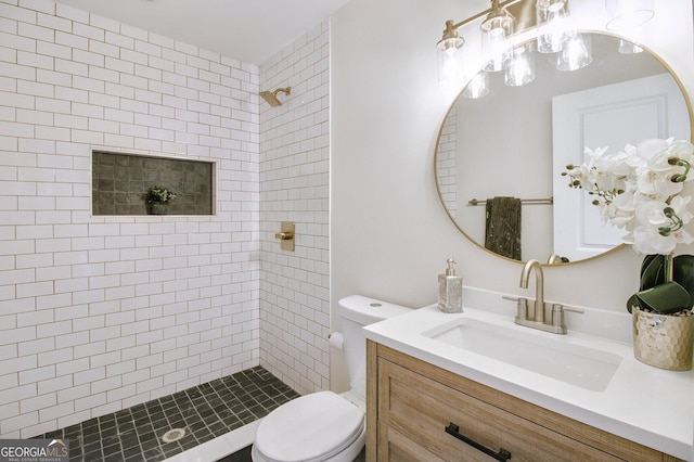 bathroom featuring vanity, toilet, and a tile shower