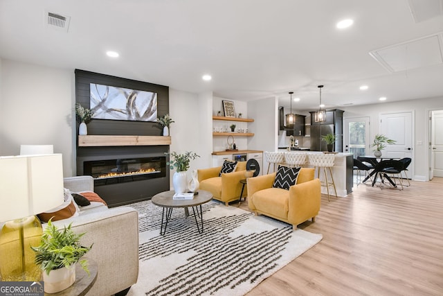 living room featuring a large fireplace and light hardwood / wood-style flooring