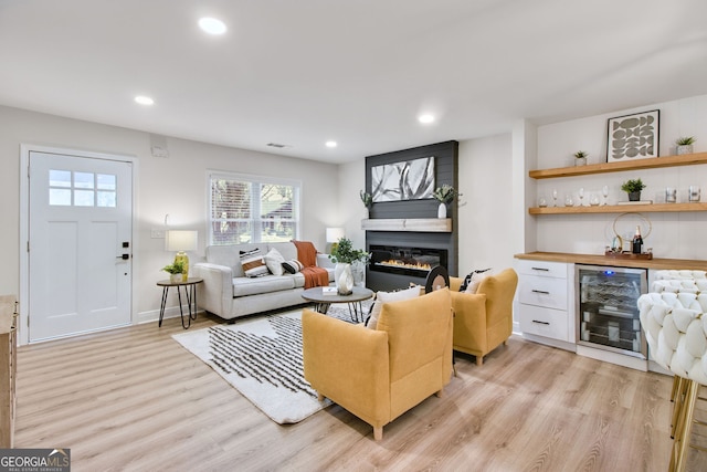 living room with a fireplace, light hardwood / wood-style floors, beverage cooler, and indoor bar