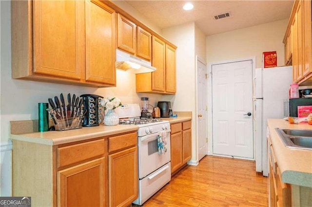 kitchen featuring sink, white appliances, and light wood-type flooring