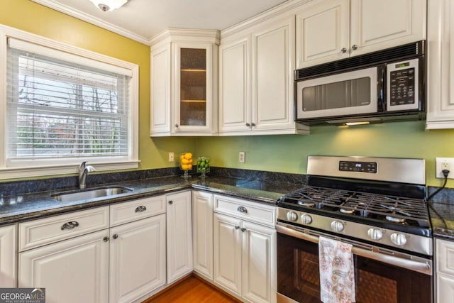 kitchen featuring stainless steel appliances, white cabinetry, sink, and dark stone counters