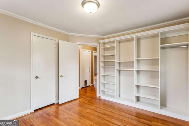 unfurnished bedroom featuring hardwood / wood-style flooring, ornamental molding, and a closet