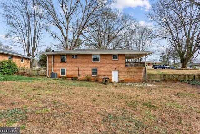 back of property with central AC and a lawn