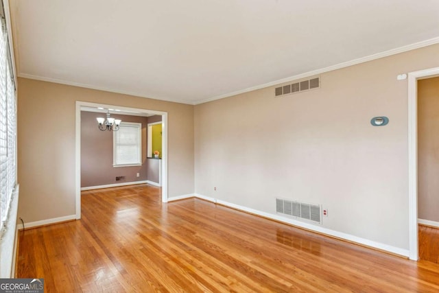 empty room with crown molding, wood-type flooring, and a notable chandelier