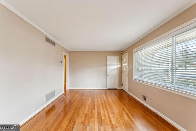 unfurnished room with ornamental molding and light wood-type flooring