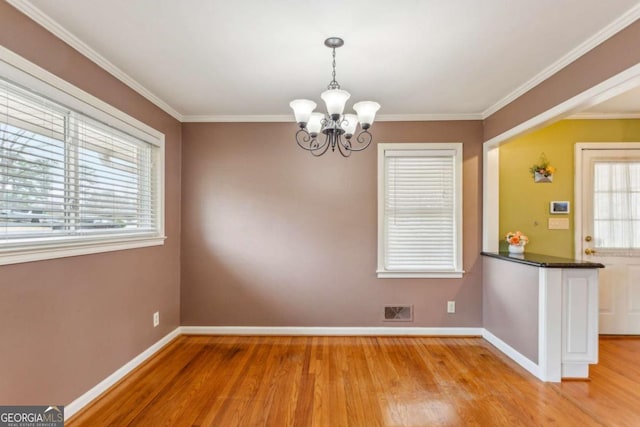 unfurnished dining area featuring ornamental molding, a notable chandelier, and light hardwood / wood-style floors