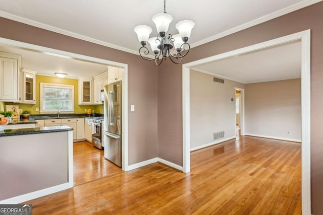 kitchen with decorative light fixtures, a chandelier, stainless steel appliances, crown molding, and light wood-type flooring