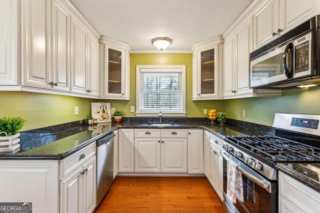 kitchen featuring white cabinetry, wood-type flooring, sink, dark stone countertops, and stainless steel appliances