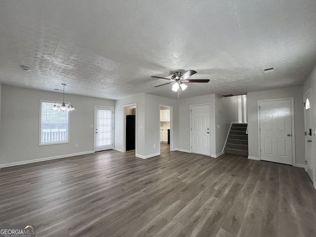 unfurnished living room featuring dark hardwood / wood-style floors, ceiling fan with notable chandelier, and a textured ceiling