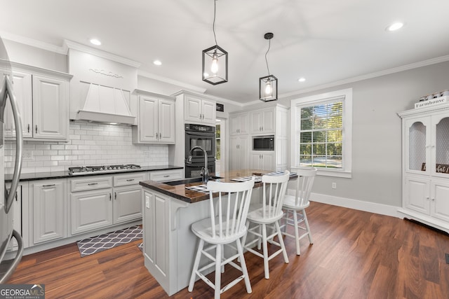 kitchen featuring white cabinetry, a center island with sink, and black appliances