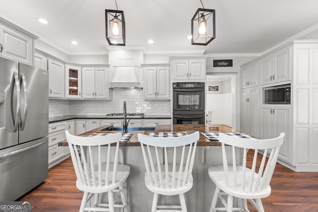 kitchen with premium range hood, decorative light fixtures, dark hardwood / wood-style flooring, a kitchen breakfast bar, and black appliances