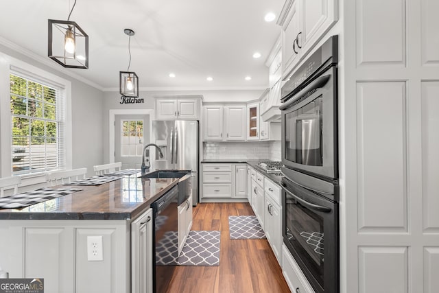 kitchen with crown molding, black appliances, hanging light fixtures, a kitchen island with sink, and white cabinets