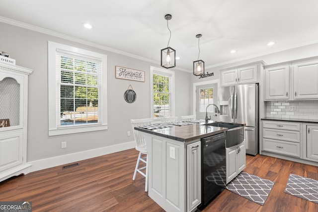 kitchen featuring pendant lighting, black dishwasher, stainless steel fridge, a kitchen breakfast bar, and a kitchen island with sink