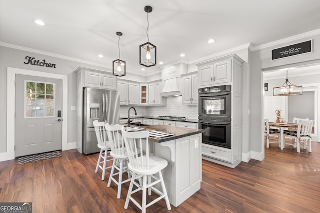 kitchen with a breakfast bar area, hanging light fixtures, a center island with sink, dark hardwood / wood-style floors, and stainless steel appliances