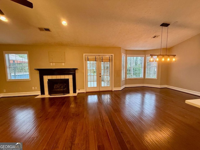 unfurnished living room with a fireplace, dark wood-type flooring, and a healthy amount of sunlight